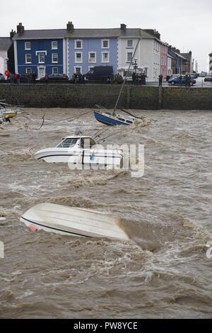 Aberaeron, UK. 13 octobre 2018. Une scène de dévastation à Aberaeron Harbour sur la côte ouest du pays de Galles cet après-midi que de fortes pluies et des vents forts de storm Callum continuent de causer du grabuge. L'eau des crues de la rivière Aeron exerçant son activité sous les arbres et grosses branches tomber sur des bateaux amarrés là dommages à de nombreux et totalement naufrage d'autres. Crédit : Anthony Pugh/Alamy Live News Banque D'Images