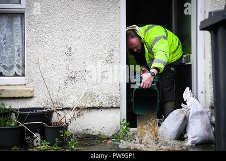 Samedi 13 octobre 2018. Tonna, South Wales, UK. Les inondations effectuée les villages d'Aberdulais et Tonna dans la Neath Valley après la tempête Callum a de fortes pluies et au vent pour la zone d'Neath River pour atteindre le point de rupture. Un homme essaye de vider sa maison de l'eau à côté du canal, Tonna, Neath. Robert Melen/Alamy Live News. Banque D'Images