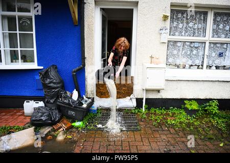 Samedi 13 octobre 2018. Tonna, South Wales, UK. Les inondations effectuée les villages d'Aberdulais et Tonna dans la Neath Valley après la tempête Callum a de fortes pluies et au vent pour la zone d'Neath River pour atteindre le point de rupture. Une femme verse de l'eau de sa maison à côté du canal, Tonna, Neath. Robert Melen/Alamy Live News. Banque D'Images