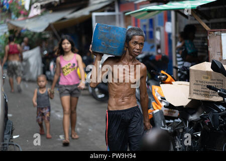 Un homme portant un récipient en plastique dans un bidonville de la ville de Cebu, Philippines Banque D'Images