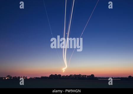 Les sentiers de la lumière de l'avion pendant l'atterrissage à l'aéroport après le coucher du soleil. Prague, République tchèque. Banque D'Images