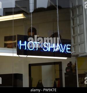 Un tube néon signe dans un salon de coiffure pour une publicité de la fenêtre 'Hot-rasage" au Royaume-Uni, Europe Banque D'Images