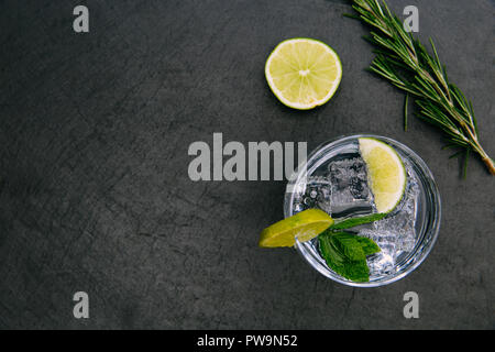 Verre à cocktail gin tonic avec verre de glace citron vert vert sur fond sombre Banque D'Images