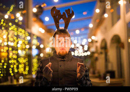 Les gens, les vacances de Noël - concept et surpris l'homme dans les cornes de cerf tenant deux baguettes à la lumière ou à l'extérieur des bengals Banque D'Images