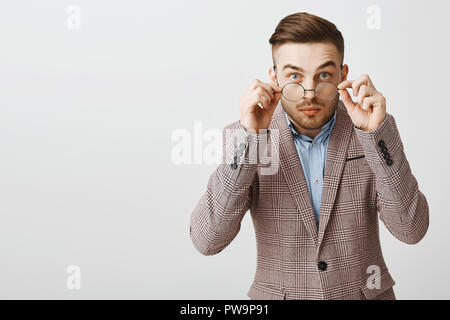 Taille plan sur l'accent caucasien attrayante intelligente jeune mec avec des lunettes en coupe de l'étonnement et la fixer à l'appareil photo comme si intrigué audience nouvelles excitantes sur fond gris Banque D'Images