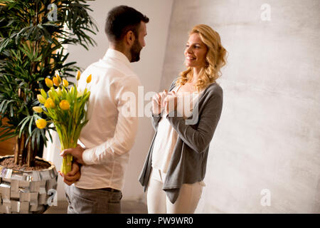 Voir à man giving bouquet de tulipes jaunes à sa petite amie Banque D'Images