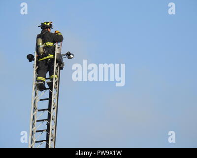 Un pompier monte une échelle tout en combattant un incendie mortel dans une maison de milieu de rue au 2551 San Pablo Ave. À Oakland le 27 mars 2017. Banque D'Images