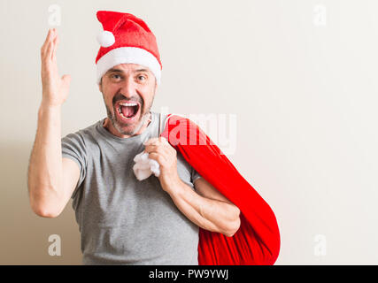 Senior man wearing christmas santa claus hat très heureux et excité, lauréat expression célébrant la victoire de crier avec grand sourire et mains levées Banque D'Images