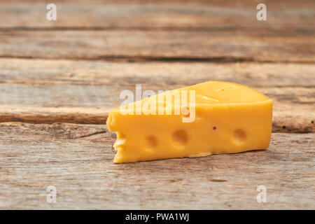 Morceau de fromage suisse sur fond de bois. Fromage avec des trous sur les planches de bois rustique. De délicieux produits laitiers. Banque D'Images