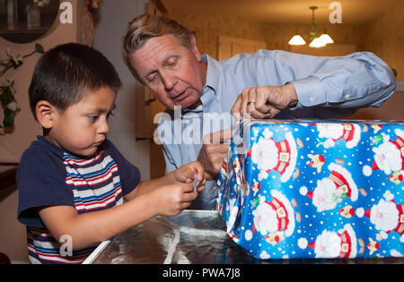 Jeune enfant cadeau de Noël d'enrubannage. Avec l'aide de papi Série de 7 images. M. © Myrleen Pearson ...Ferguson Cate Banque D'Images