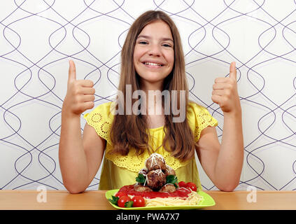 Happy girl with spaghetti et boulettes de viande et de Thumbs up Banque D'Images