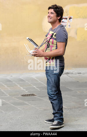 Jeune homme à l'essai d'un drone sur l'Ospedale del Ceppo dans la Piazza Giovanni, de la vieille ville de Pistoia, Toscane, Italie, Europe, Banque D'Images