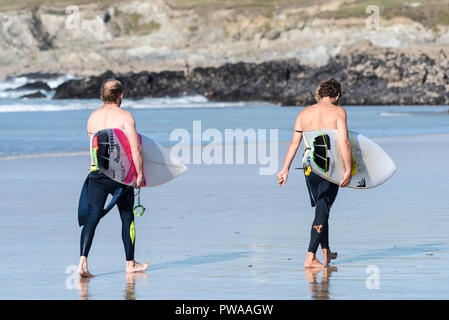 Deux surfeurs de marche de la mer avec leurs planches de surf sur la plage de Fistral à Newquay en Cornouailles. Banque D'Images