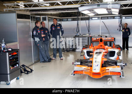 F1 au travail mécanique sur une voiture de course F1 dans l'atelier de la voie des stands de Silverstone Banque D'Images