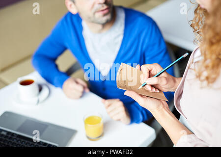 Serveuse de cafe l'écriture de commande petit-déjeuner d'affaires dans le bloc-notes Banque D'Images