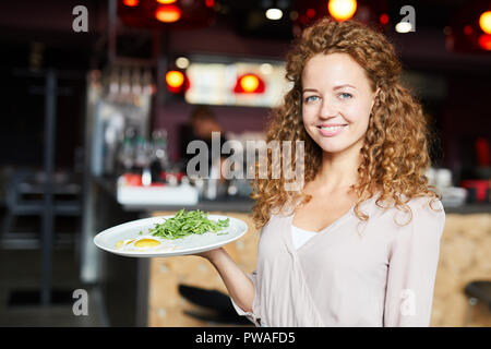 Waitress dans casualwear portant la plaque à l'ordre du client tout en travaillant dans un café ou restaurant Banque D'Images