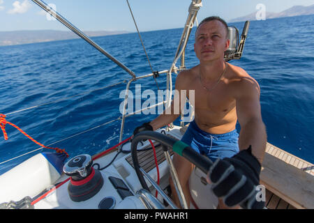Homme skipper steers les commandes d'un yacht à voile. Banque D'Images