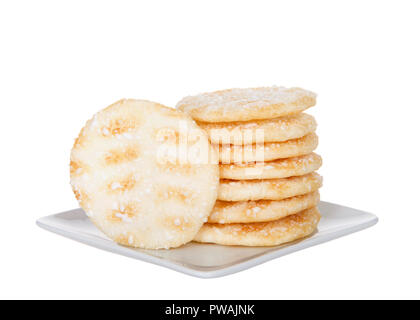 Pile de craquelins de riz japonais sur un petit carré blanc Assiette de porcelaine isolé sur fond blanc. Craquelins au riz sont habituellement faibles en sucre et graisse. Banque D'Images