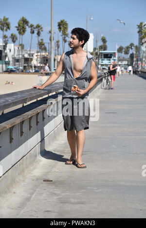 Un beau jeune homme multi-ethnique de manger une pointe de pizza en marchant sur le quai Banque D'Images