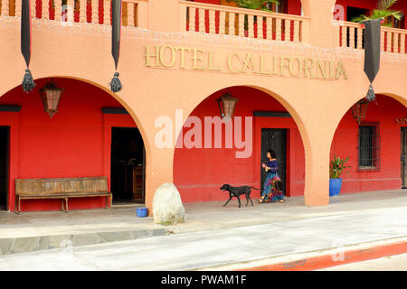 Une femme et son chien passent devant l'Hôtel California à Todos Santos, Mexique. Banque D'Images