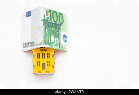 Maison de miniatures sous l'euro argent pliée dans la forme d'une maison isolé sur fond blanc. Banque D'Images