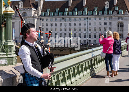 Un homme joue de la cornemuse sur le pont de Westminster, Londres, Angleterre Banque D'Images