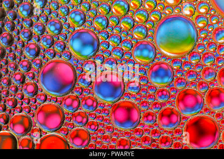 Résumé Les gouttelettes d'huile / bulles dans l'eau allumé par le bas sur un fond coloré Banque D'Images
