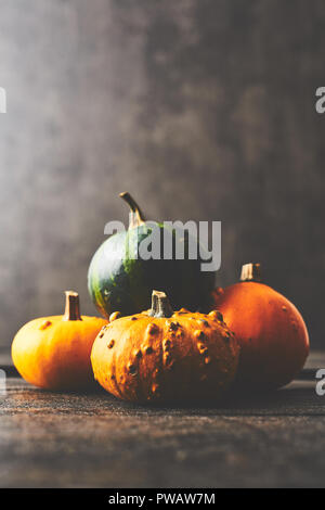 Un tas de citrouilles sur table rustique en bois noir foncé sur fond de béton avec l'exemplaire de l'espace. Vintage style rétro. Focus sélectif. Banque D'Images