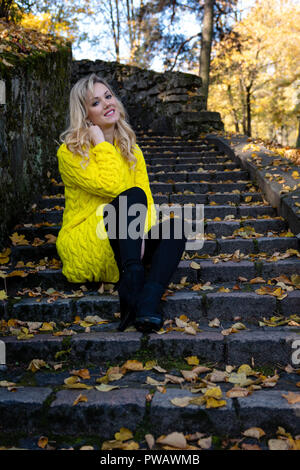 Jeune, belle, blonde femme est assise dans le parc sur une Vieille échelle. Banque D'Images