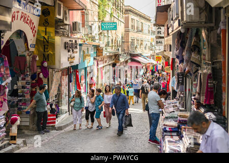 Rangées de magasins avec des marchandises sur la ligne d'affichage rue pavée en pente avec les gens et les touristes à marcher le long dans le district de Fatih, Istanbul, Turquie Banque D'Images