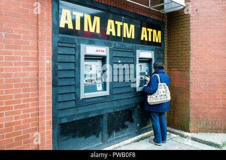 Une femme de retirer de l'argent dans un distributeur automatique. Banque D'Images