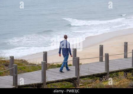 Homme marchant sur une promenade à la plage par temps froid Banque D'Images