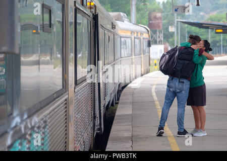 Deux personnes serrant en disant au revoir à l'un l'autre avant de s'embarquer dans un train à une gare ferroviaire de la plate-forme Banque D'Images