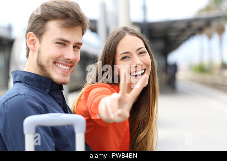 Couple d'heureux voyageurs posing looking at camera dans une gare Banque D'Images