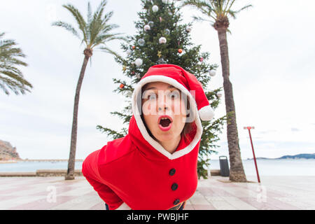 Noël, les vacances et plaisanterie drôle - concept surpris femme en costume de Père Noël en plein air Banque D'Images