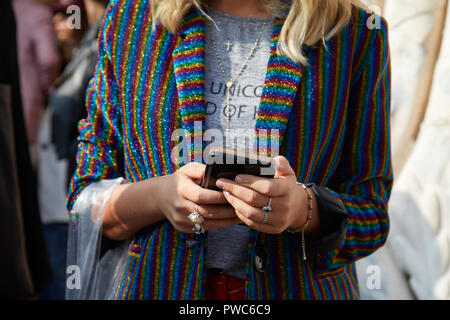 MILAN, ITALIE - 20 septembre 2018 : Femme avec veste à rayures glitter looking at smartphone avant de Genny fashion show, Milan Fashion Week stre Banque D'Images