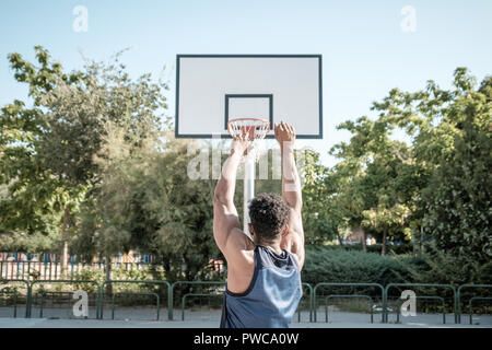 Close-up de l'arrière de l'un afroamerican jeune homme jouant au basket-ball dans un parc de Madrid au cours de l'été à midi. Il est le tir de la balle à la Banque D'Images