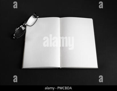 Livre ouvert blanc et verres sur fond noir. Responsive design immersive. Banque D'Images