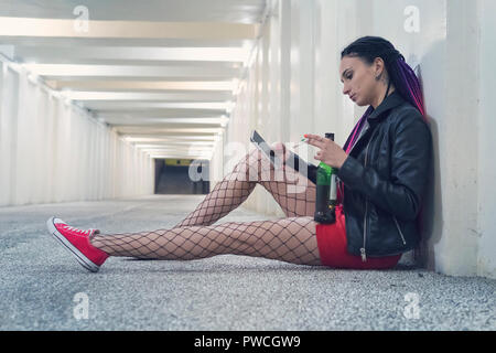 Jeune fille déprimée de boire de l'alcool et du tabac dans le souterrain dans l'attente d'appel important. femme regarde l'écran du smartphone avec un Banque D'Images