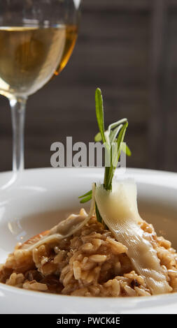 Plat italien risotto aux champignons sauvages et parmesan dans une assiette blanche. Banque D'Images