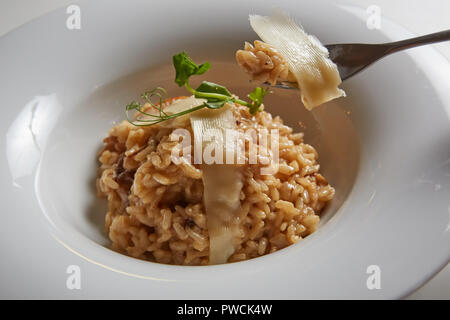 Plat italien risotto aux champignons sauvages et parmesan dans une assiette blanche. Banque D'Images