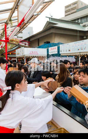 Nouvel An japonais, shogatsu. Shrine Maidens, Miko, occupé à lutter contre la vente de papier des feuillets d'omikuji fortune à Ikuta Temple Shinto à Kobe. Banque D'Images