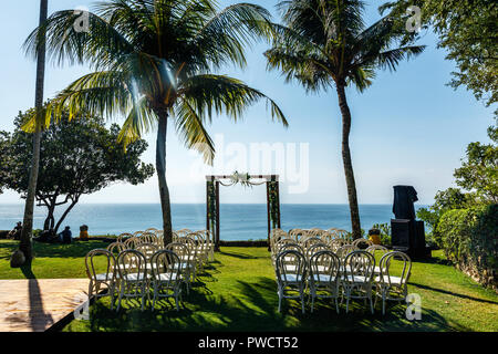 Arche de mariage pour une cérémonie décorée de fleurs fraîches, des chaises pour les invités au milieu des palmiers près de l'océan. Concept d'un mariage tropical. Banque D'Images