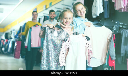 Deux sœurs heureux avec les parents satisfaits de vos achats au magasin de vêtements pour enfants Banque D'Images