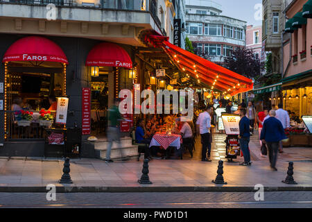 Un restaurant avec salle à manger extérieure au crépuscule lorsque les gens passent devant, Istanbul, Turquie Banque D'Images