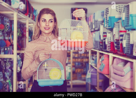 Le choix d'une femme petite cage dans pet shop Banque D'Images