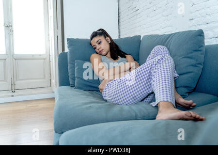 Belle jeune femme latine allongé sur le canapé un sentiment de tristesse, de désespoir et de douleur souffrant de dépression dans le deuil de la santé mentale et la psychologie concep Banque D'Images