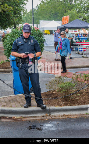 HICKORY, NC, USA-10/14/18 : un policier en service à la fête d'automne, regardant son smartphone. Banque D'Images