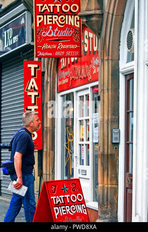 L'homme en regardant par la fenêtre avant d'aller dans un salon de tatouage et piercing studio salon salon à Matlock England UK Banque D'Images