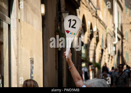 Un guide nous tend un paddle montrant le numéro 12 de son groupe, à voir et à suivre à travers les rues sinueuses de Florence, Italie. Banque D'Images